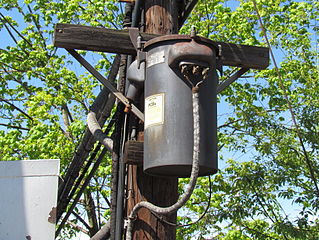Railroad signal power supply transformer dating from the 1930's at CP-SLOPE interlocking, west of: Altoona, Pennsylvania, with a warning label indicating that it contains PCBs. Photographed on 29 April 2012 by Sturmovik. Courtesy of Wikipedia